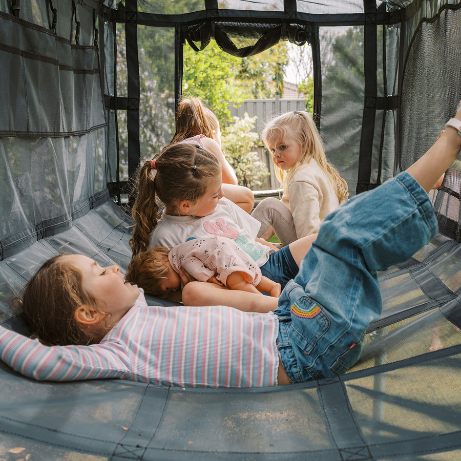 Family lying inside black Cubby Clubhouse on Funky Monkey Bars frame
