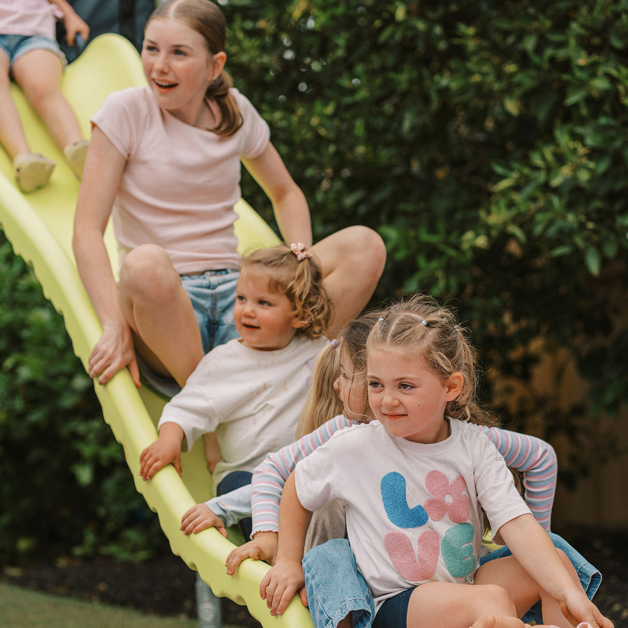 Adult helping children on yellow Cubby Clubhouse slide